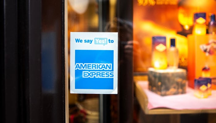 A close-up of a sticker on a shop's window advertising they accept payment with American Express.