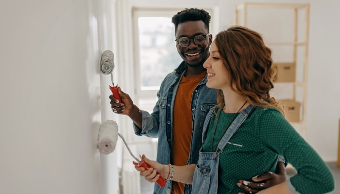 A couple smiling paining the walls of their new home