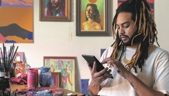 A man in an art studio looking at a tablet.