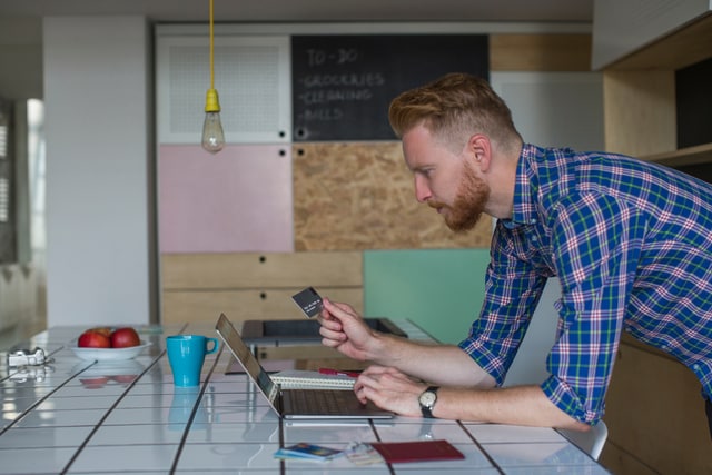 Man holding a credit card going over his finances at home.