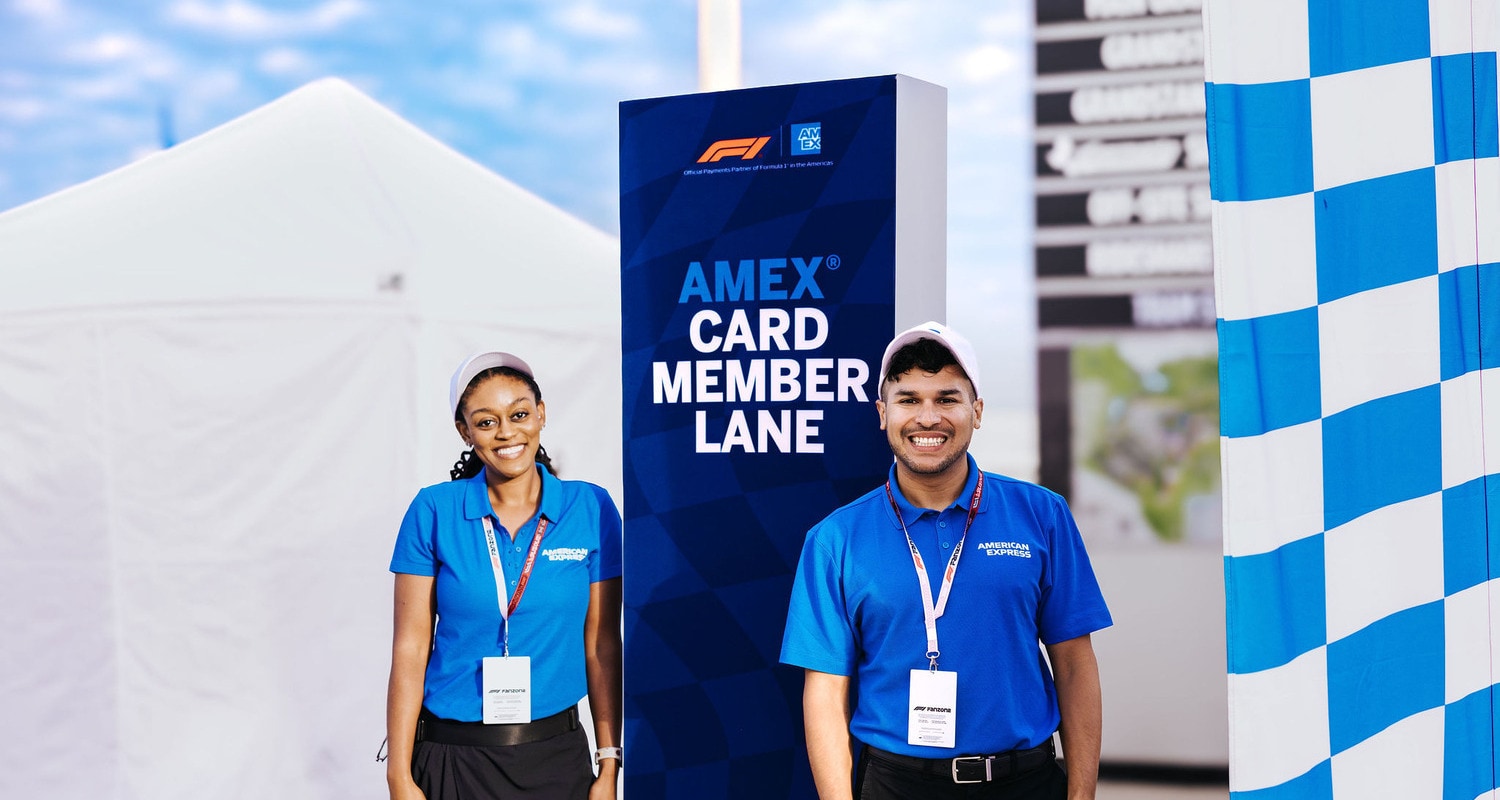 Group of people participating in a Formula 1 Driver Evaluation activity, with multiple screens and interactive stations in use.