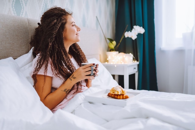 Woman having breakfast in bed in a hotel.