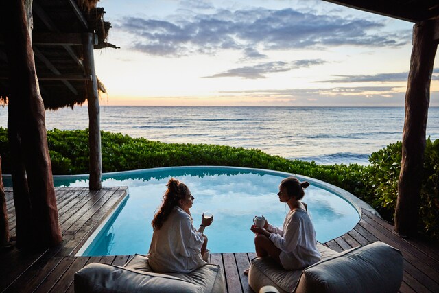 Friends in discussion while sitting poolside at luxury suite of tropical resort at sunrise.
