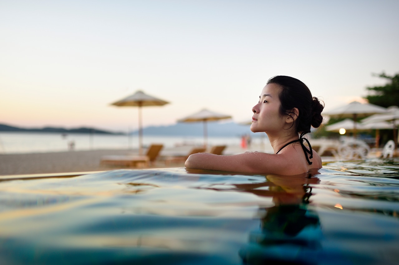 Woman relaxing at the hotel pool near the beach.