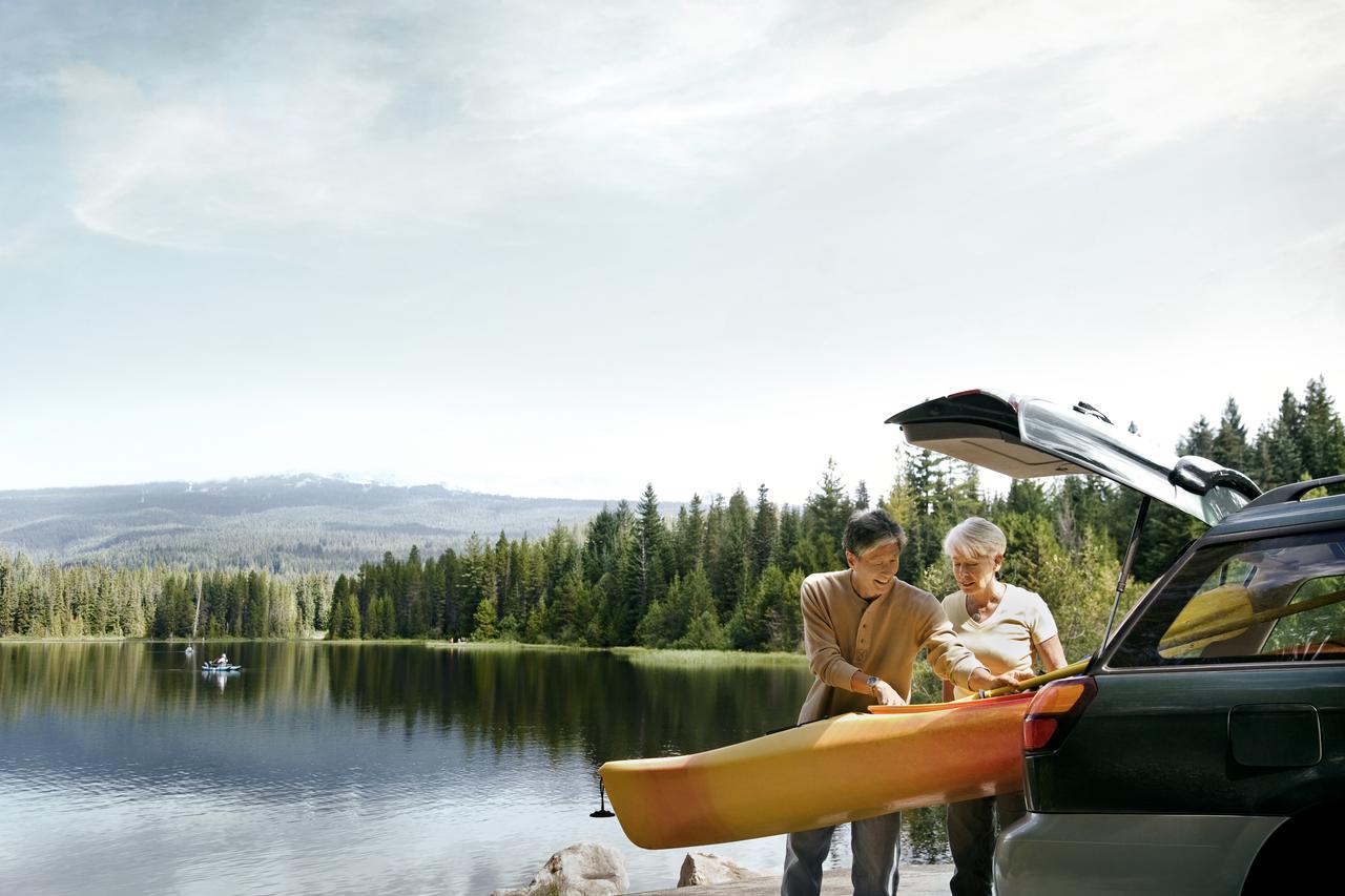 couple unloading a kayak from the car by a lake