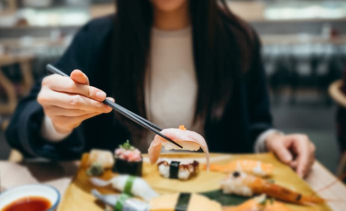 Woman holding food with chopsticks
