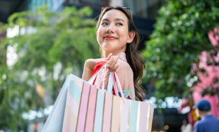  Woman standing outside with a shopping bag and smiling