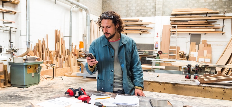 Man in workshop holding phone        