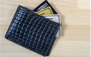 black wallet laying on table with three cards hanging out