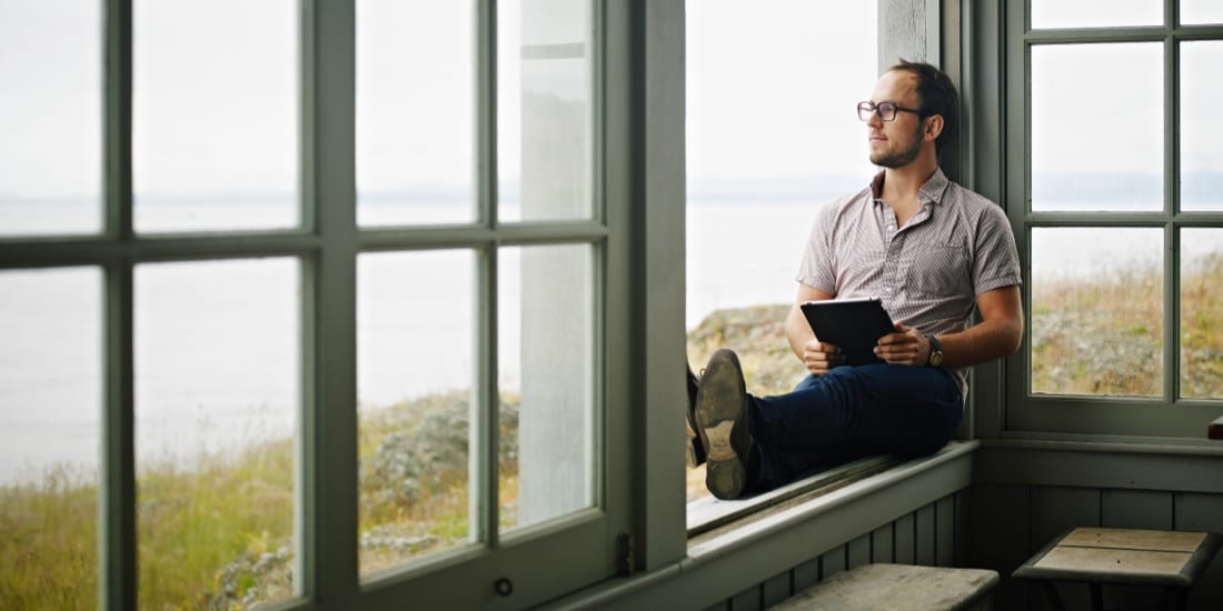 Man sitting on window sill holding tablet