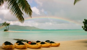 Boats on a beach with rainbow in view