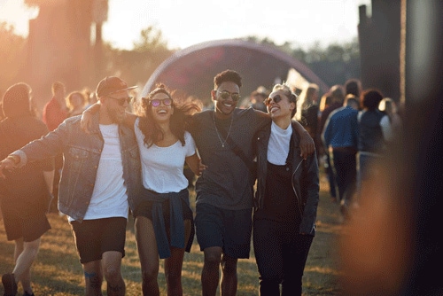 Four people with their arms around each other smiling and enjoying a festival