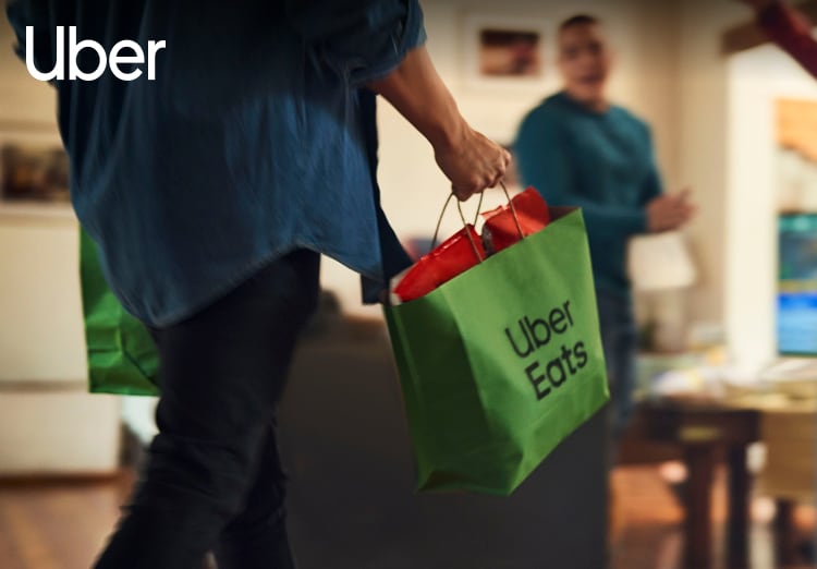 Hand carrying an Uber Eats branded bag