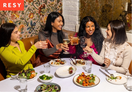 Group of women toasting at a restaurant corner booth
