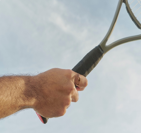 Close shot of a hand wearing an Oura ring holding a tennis racket