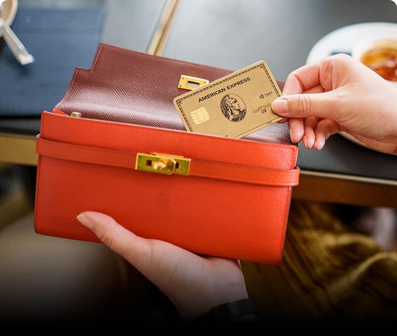 Close shot of one hand grabbing an American Express Gold Card from their wallet