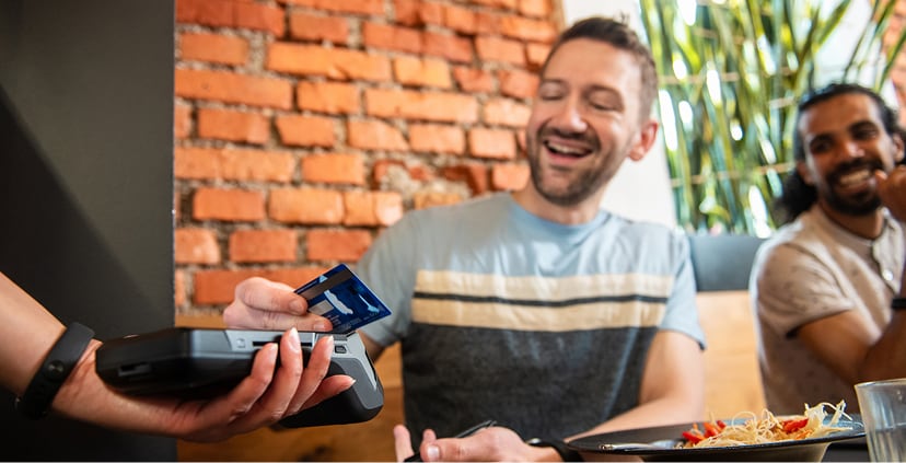 Men using tap to pay and their American Express at a restaurant