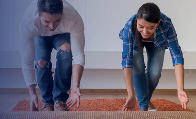 Couple rolling out carpet at home