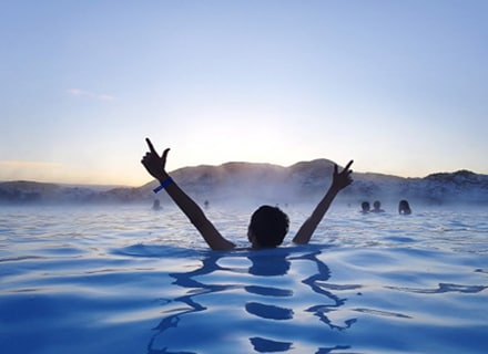 Hero image: Person swimming in water with their arms raised.