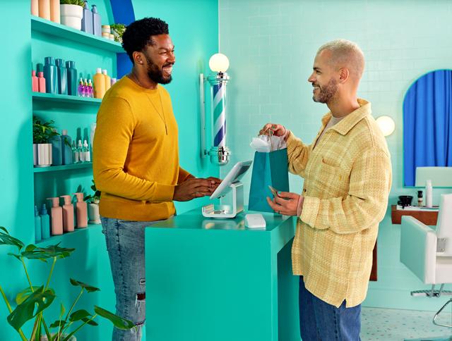 Barbershop owner chatting with customer at checkout