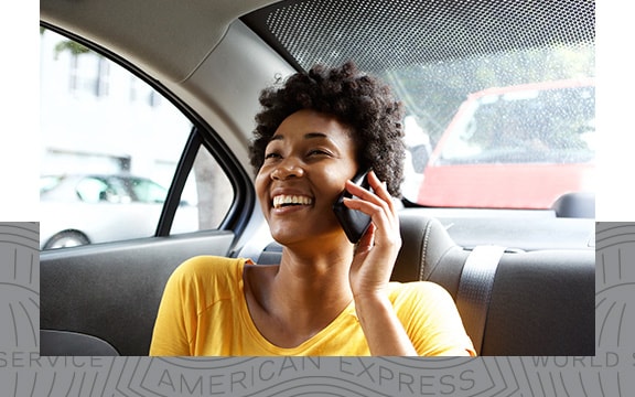 A woman smiling on the phone in the back of a car.