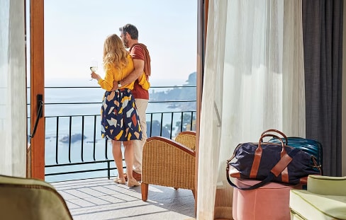 Travelers embracing on their hotel room balcony.