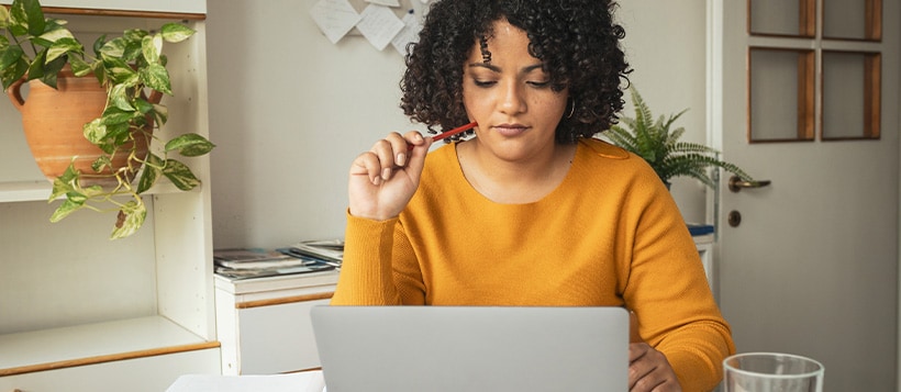 Woman sits at her table using her laptop