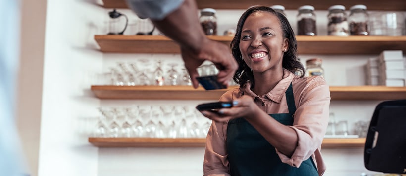 Smiling small business owner using technology to take payments from a customer.
