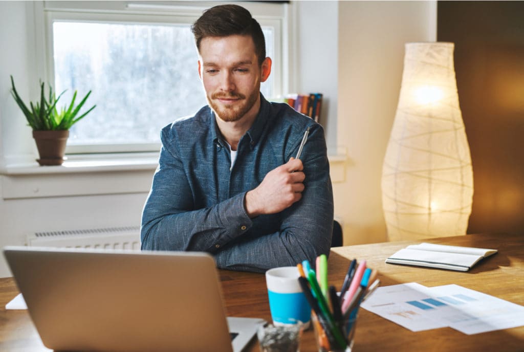 Man looking at business details on computer while smiling.