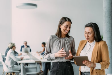 Two women talking in conference room.