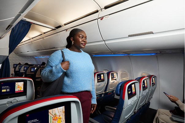 Woman walking down main aisle in airplane.