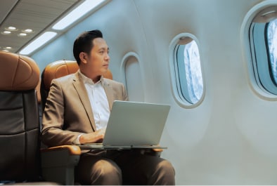 Businessman sitting in airplane with open laptop.