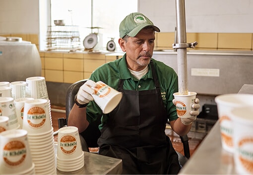 Employee in ice cream shop filling cups