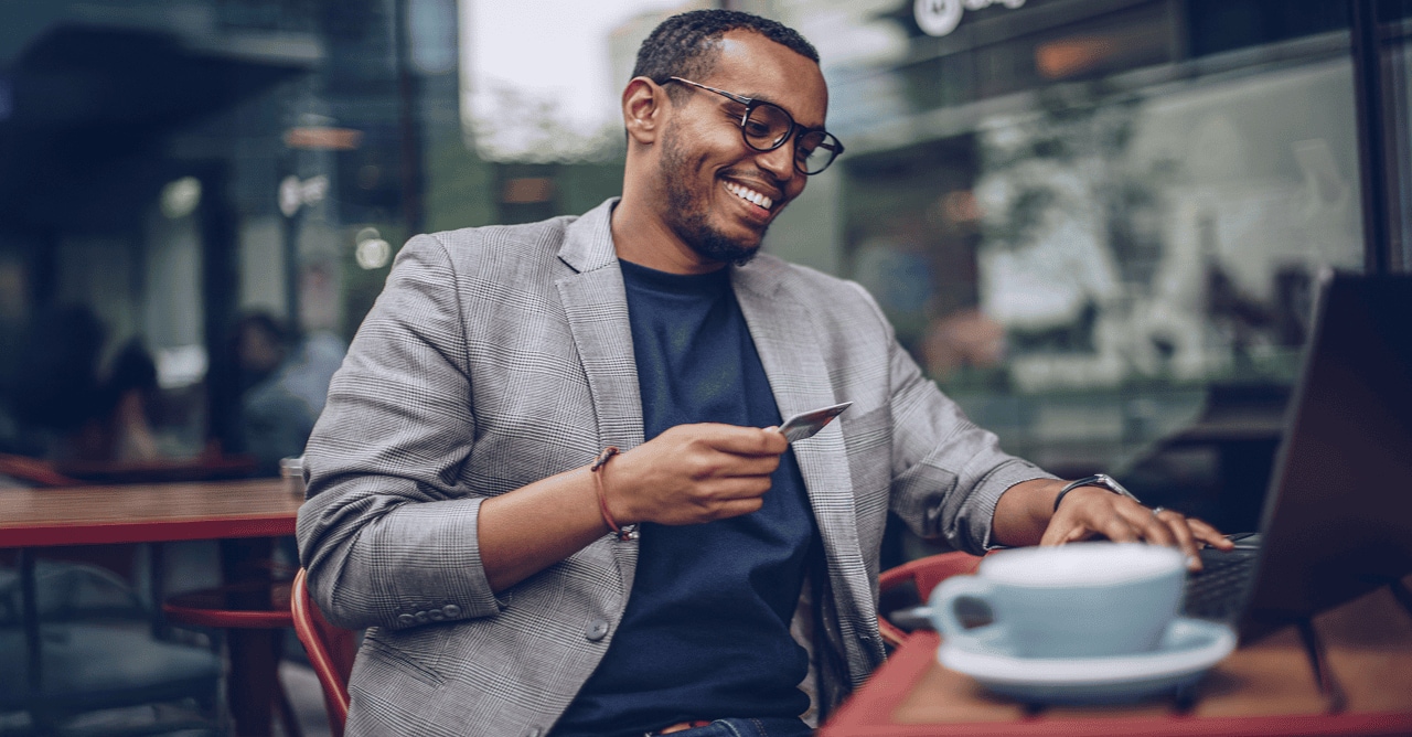Person at a coffee shop on a laptop holding their American Express card