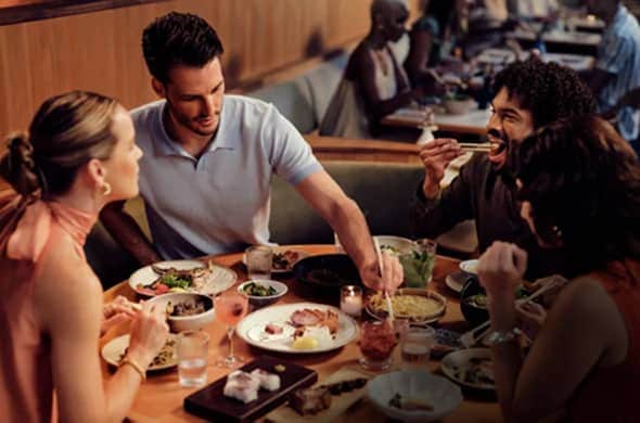People enjoying dinner at a restaurant with Resy logo