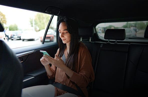 Person in the car on their phone with an Uber logo