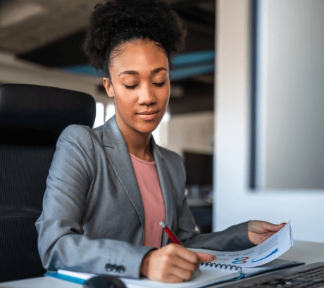 Woman sitting at desk writing in planner