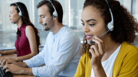 Three customer service employees sitting next to each other and taking calls