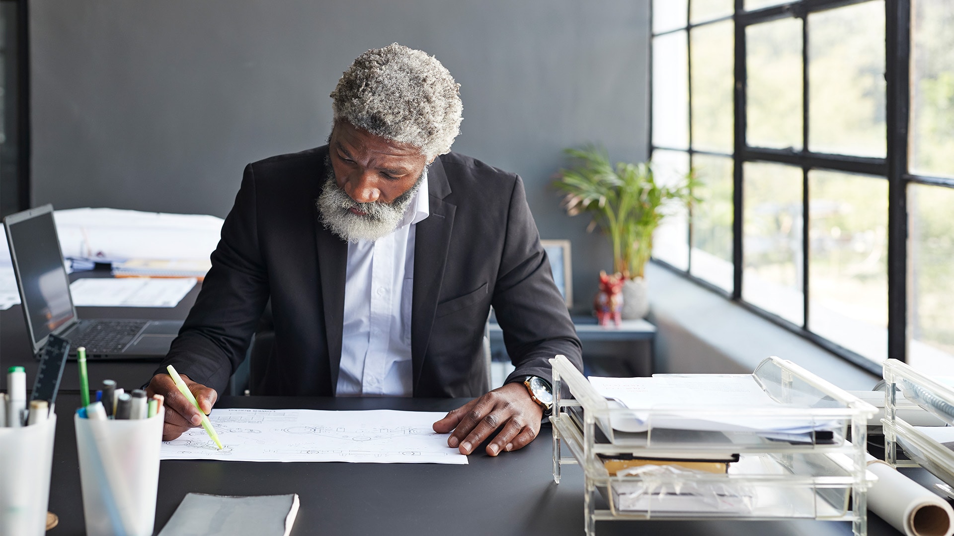 Man sitting at his desk writing notes in his notebook with a yellow highlighter