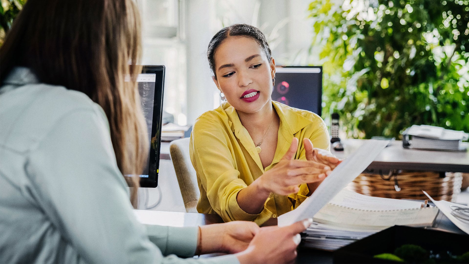 Two women at an office analyzing an article on paper