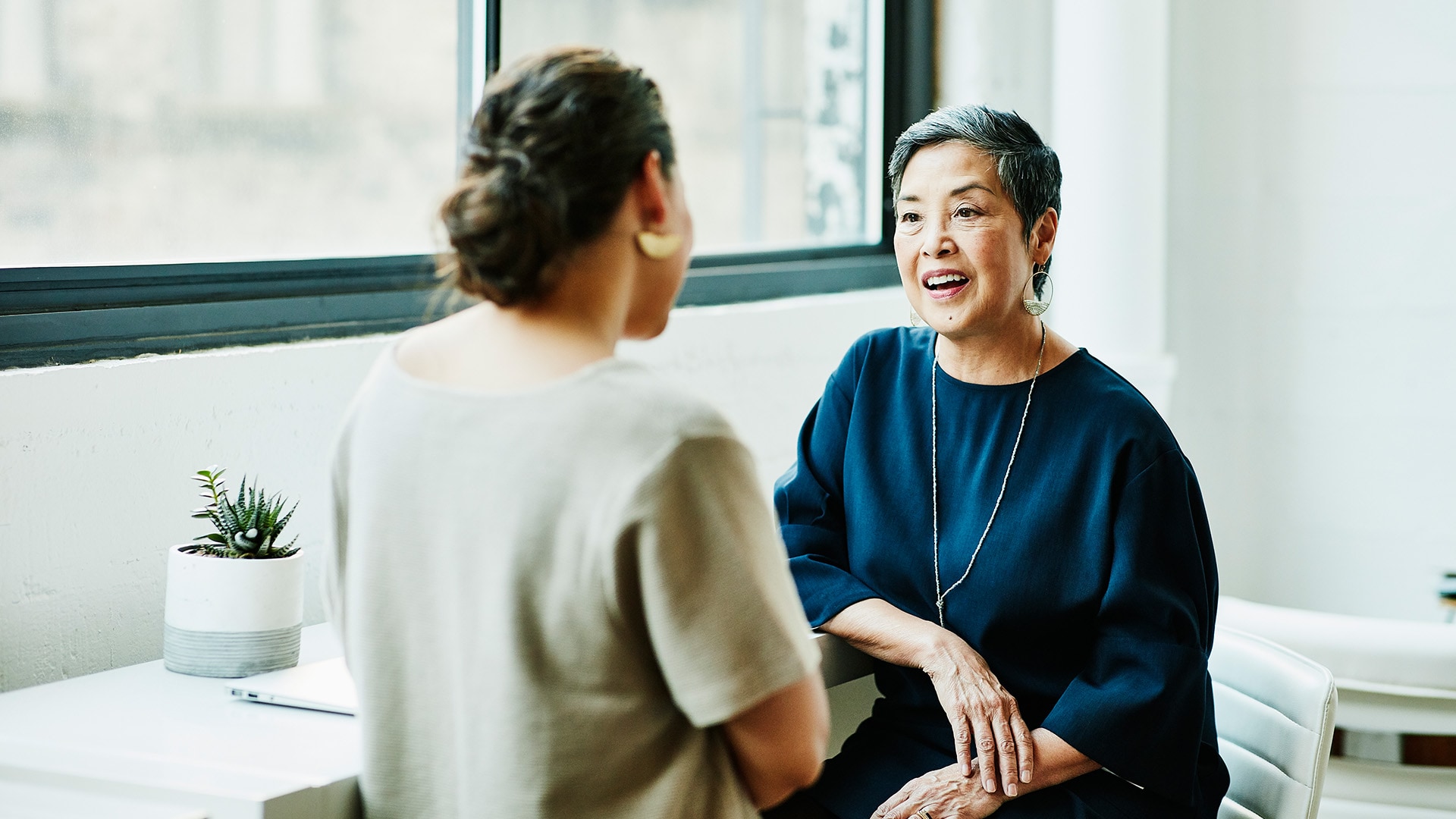 Two women sitting at an office desk discussing strategy