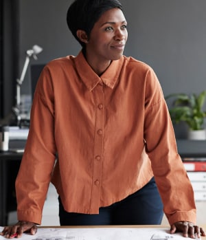 A businesswoman braces herself confidently on a table.