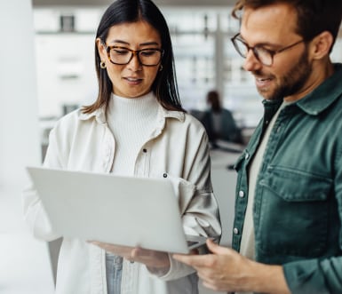 A man and a woman discuss business while looking at a laptop.