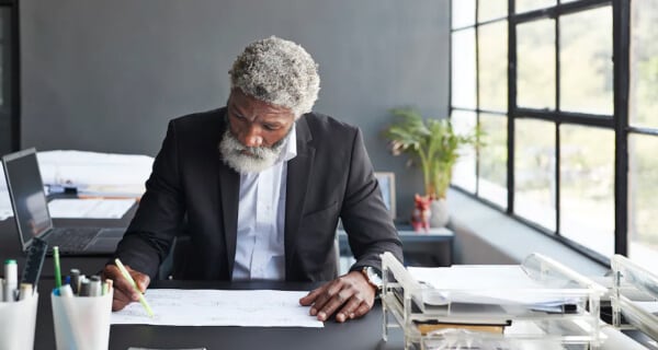Man in office marking hand-drawn plans with highlighter
