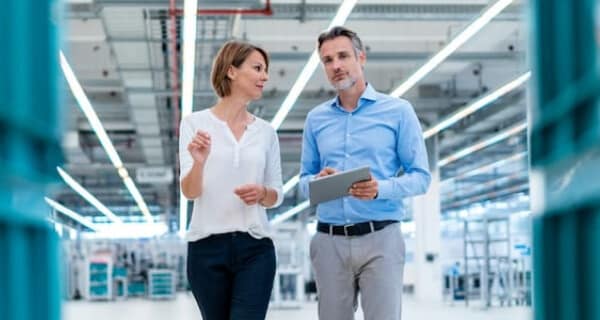 Woman and man in conversation in brightly lit warehouse