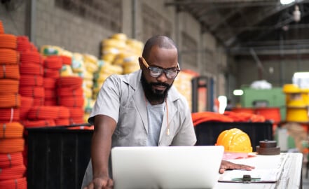Man with laptop and drafting board in a warehouse