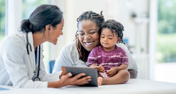 Smiling doctor showing laptop to mother and child