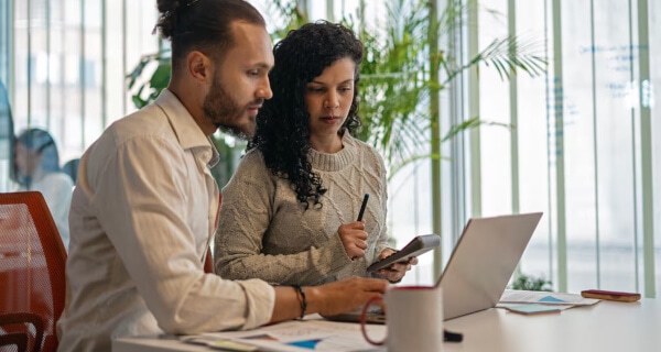 Man with laptop and woman with calculator at conference room table