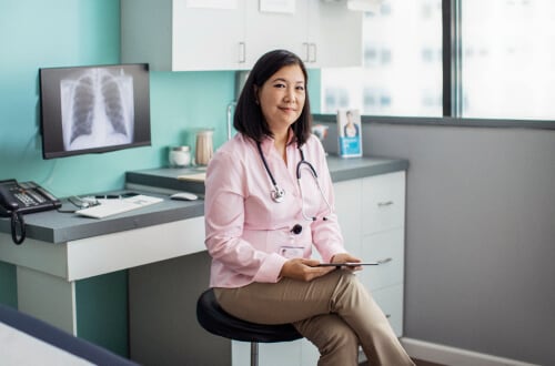 Woman with stethoscope and tablet in doctor’s office reviewing x-rays