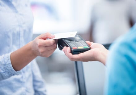 Woman tapping credit card on a credit card reader